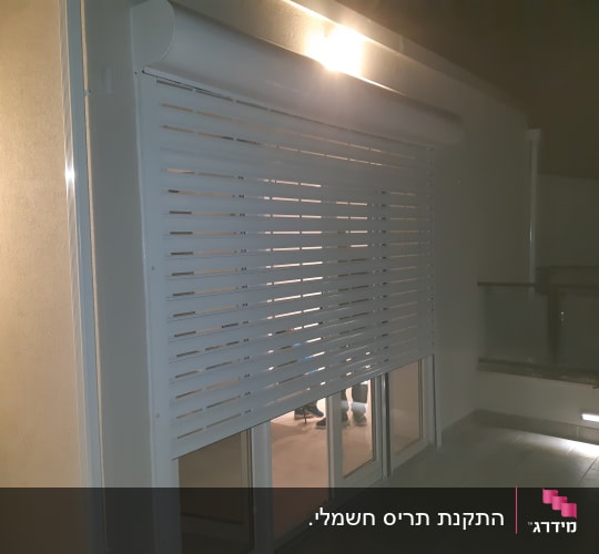 תריס אלומיניום לבן מותקן על חלון זכוכית